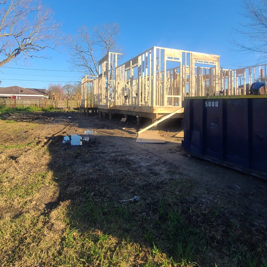 Wall framing on an elevated platform next to a construction dumpster