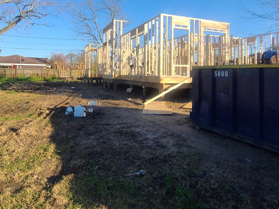 Wall framing on an elevated platform next to a construction dumpster