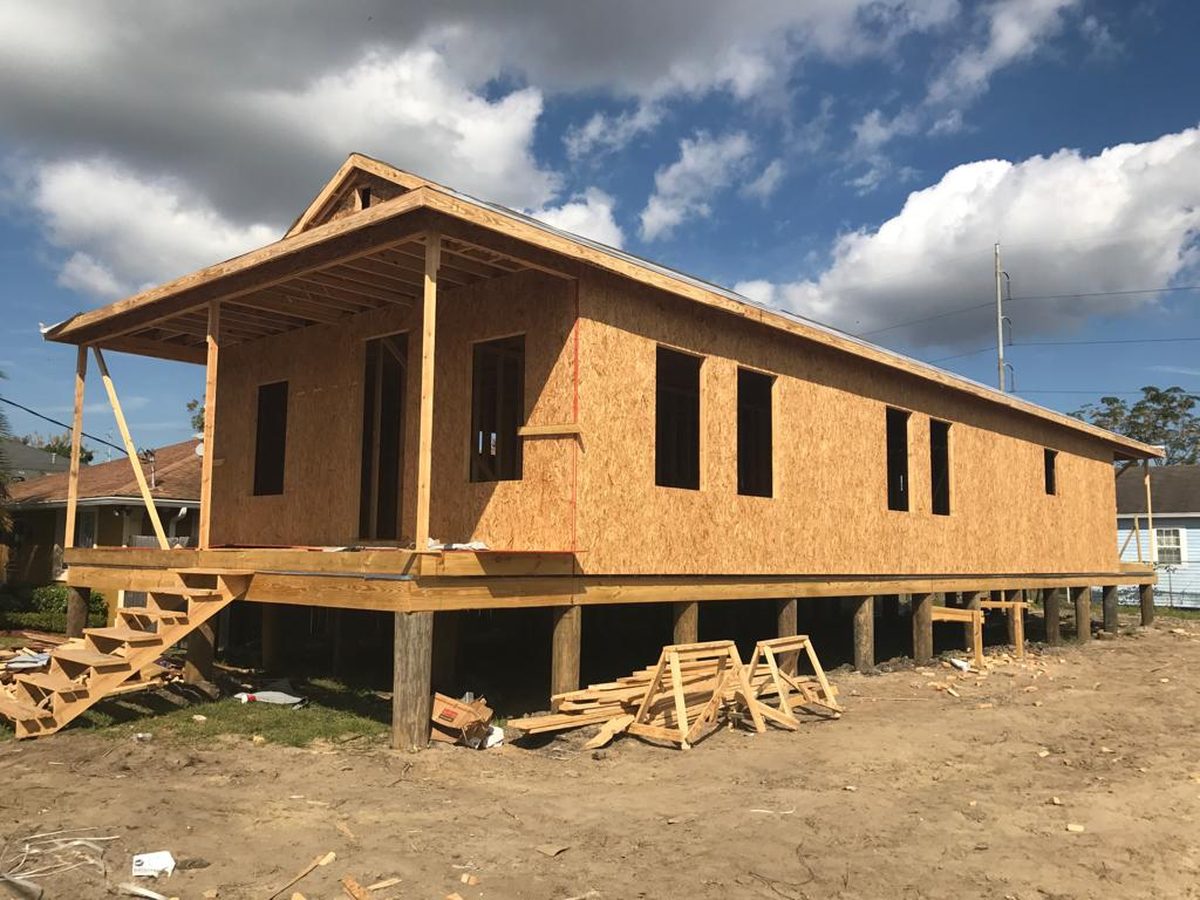 Raised new home sheathed in OSB with a framed front porch and stairs