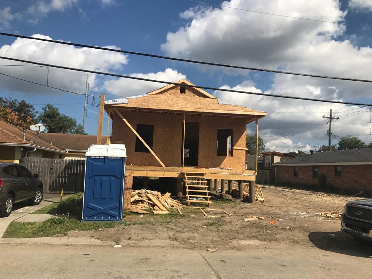 Small raised home sheathed in OSB with a framed porch and temporary stairs
