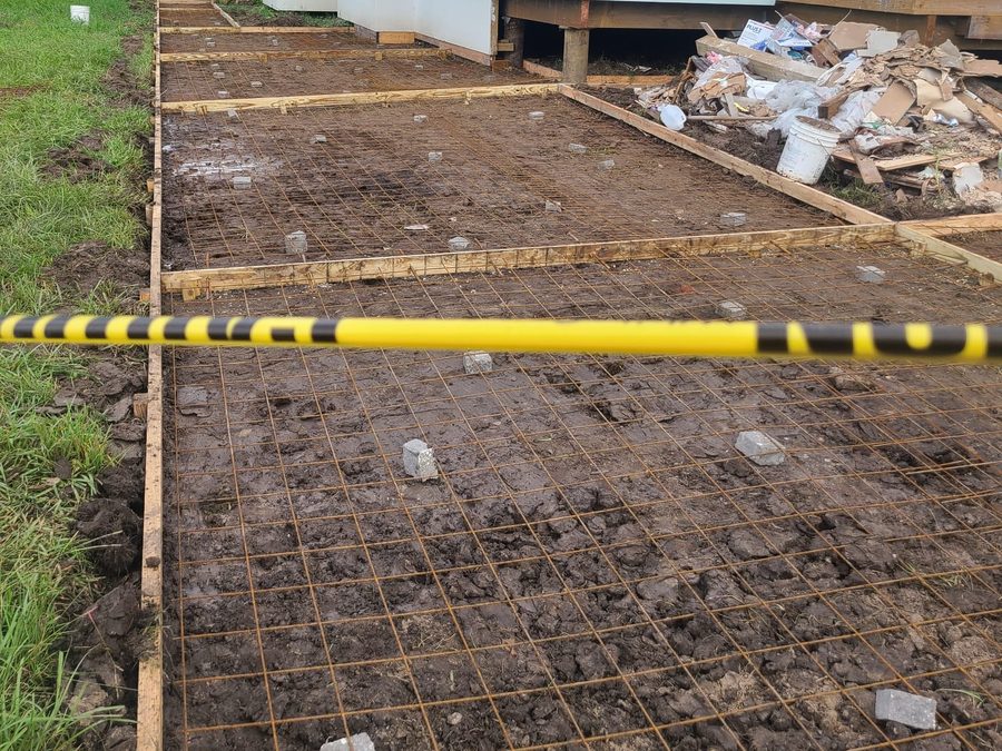Wire mesh and forms set for a concrete walkway beside a mint-green stucco home