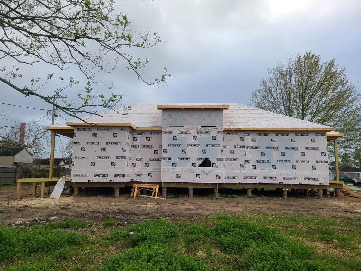 Raised home fully wrapped with a hip roof deck, viewed straight on