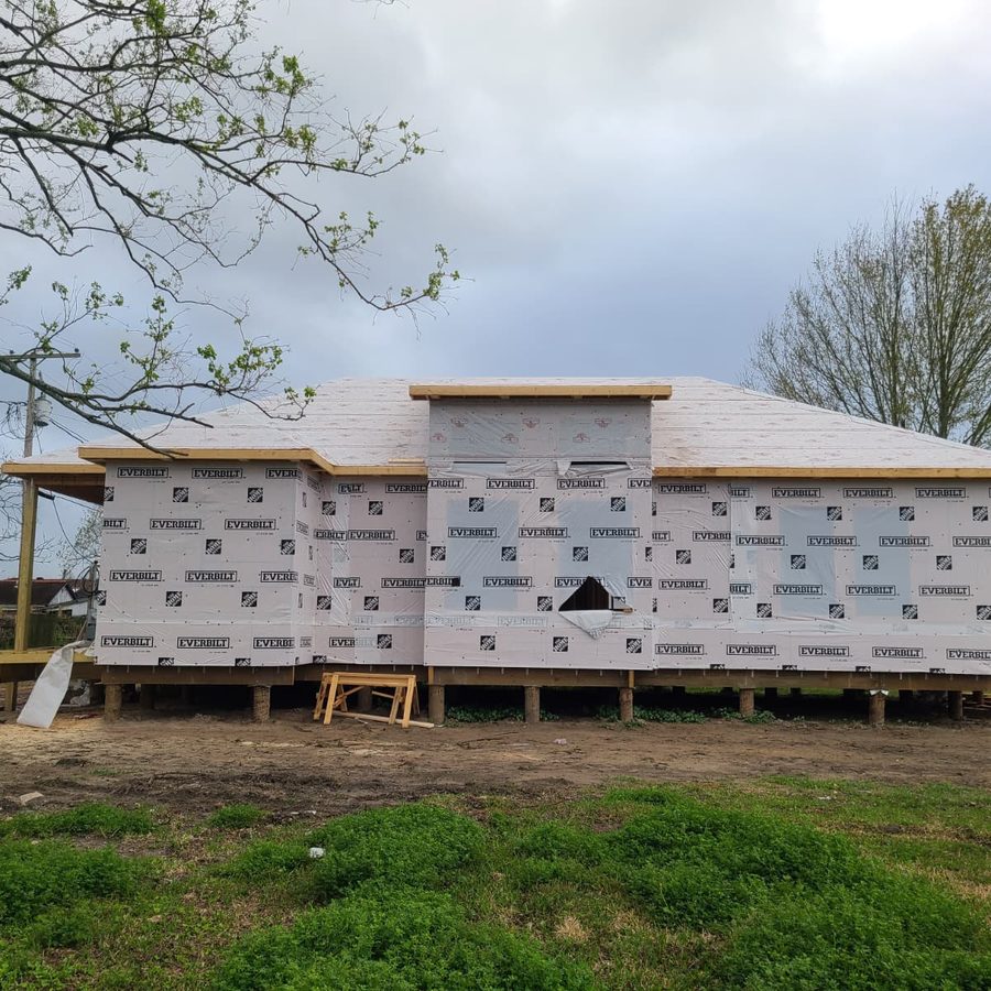 Raised home fully wrapped with a hip roof deck, viewed straight on