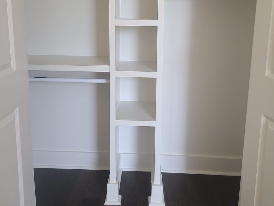 Finished white closet with a built-in shelving tower and hanging rods