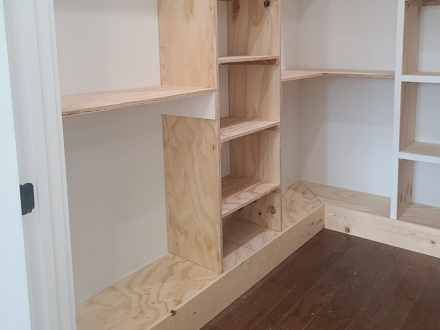 Custom walk-in closet shelving built from plywood before painting