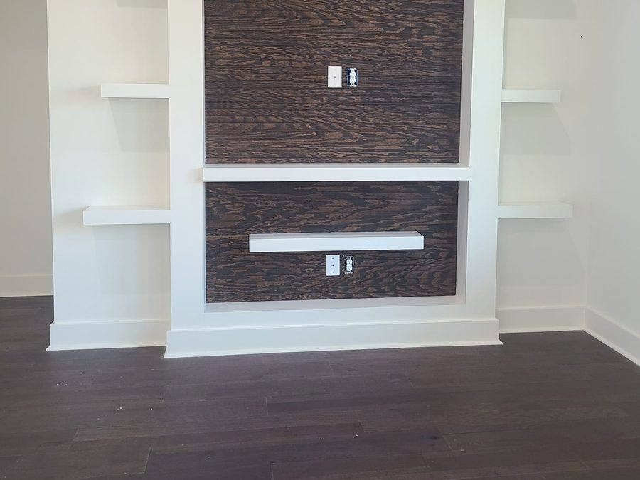 Built-in media wall with dark stained wood paneling, white columns and floating shelves