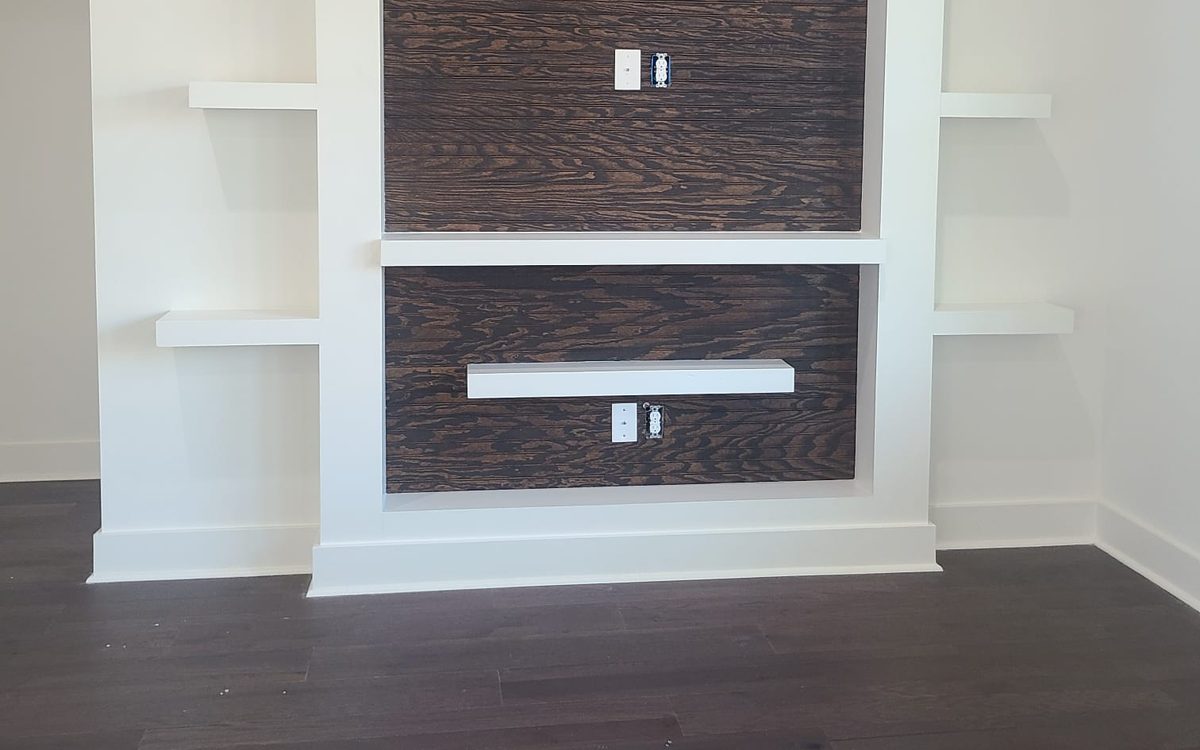 Built-in media wall with dark stained wood paneling, white columns and floating shelves