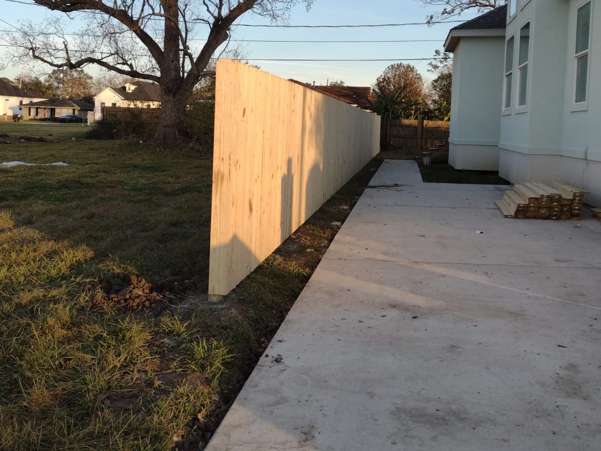 New concrete driveway running along a home beside a new wood privacy fence
