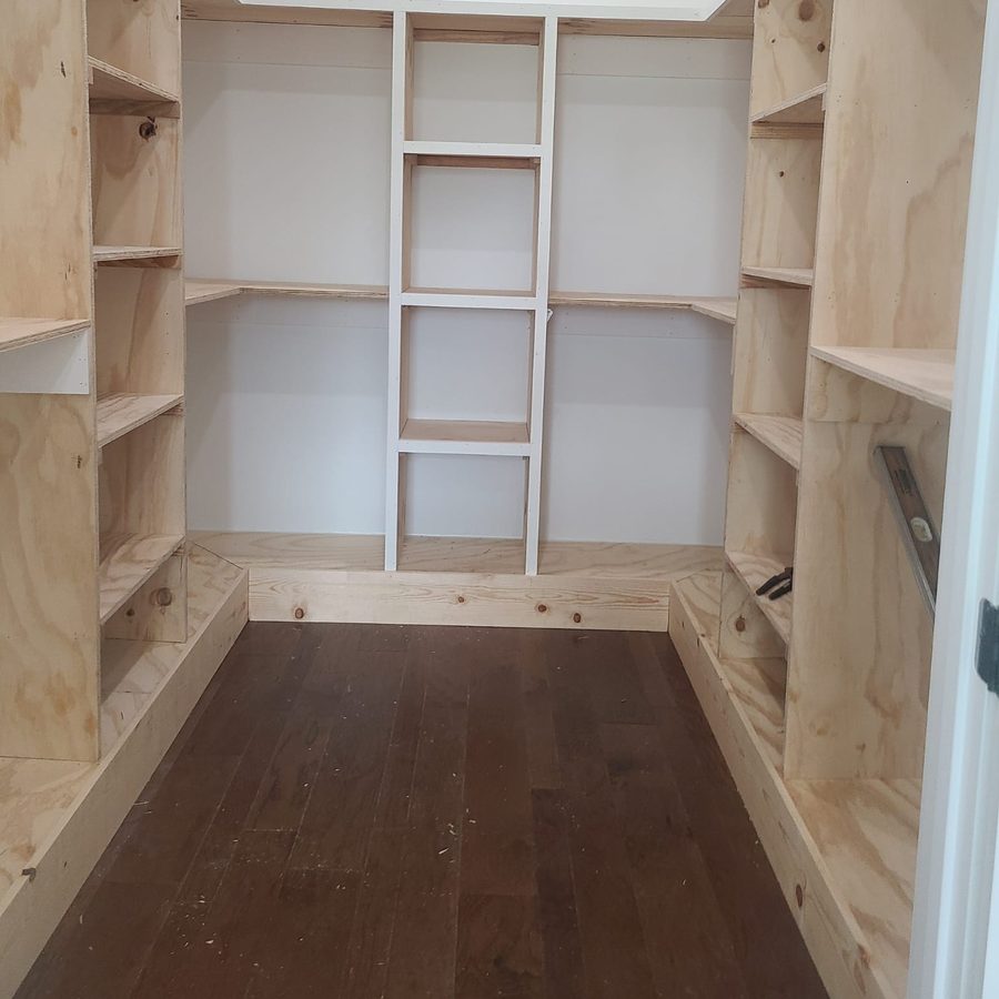 U-shaped walk-in closet with custom plywood shelving