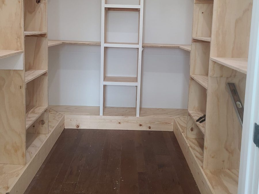 U-shaped walk-in closet with custom plywood shelving