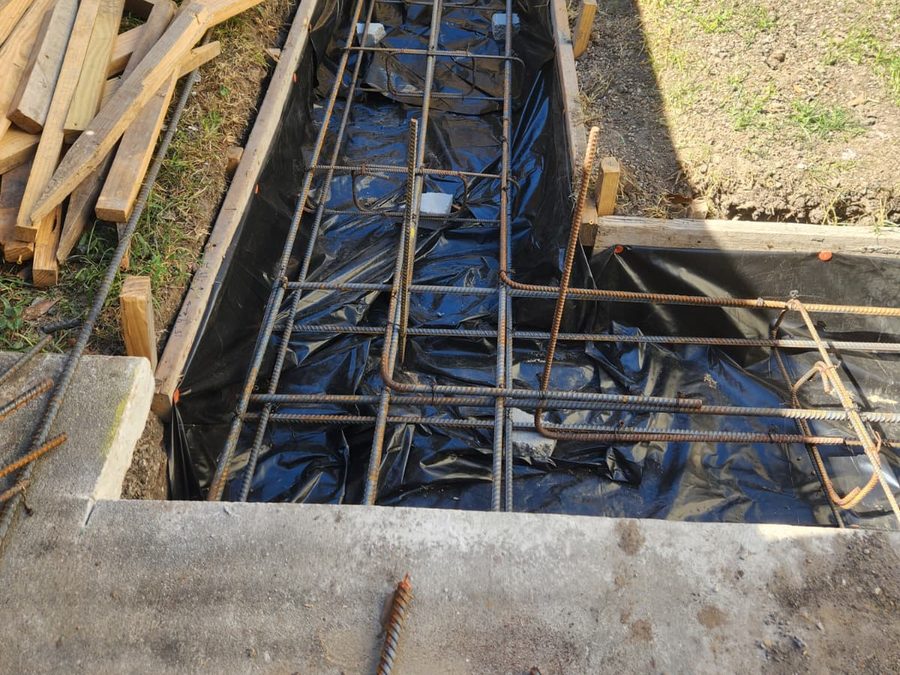 Rebar cage in a formed trench lined with plastic, ready for a concrete footing