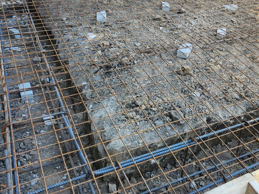 Reinforced slab forms with mesh and rebar outside a brick home
