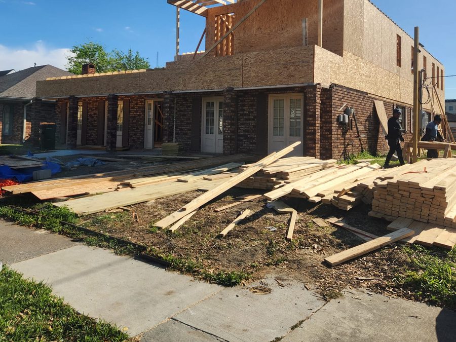 Second-story addition sheathed in OSB with a framed balcony on a brick home