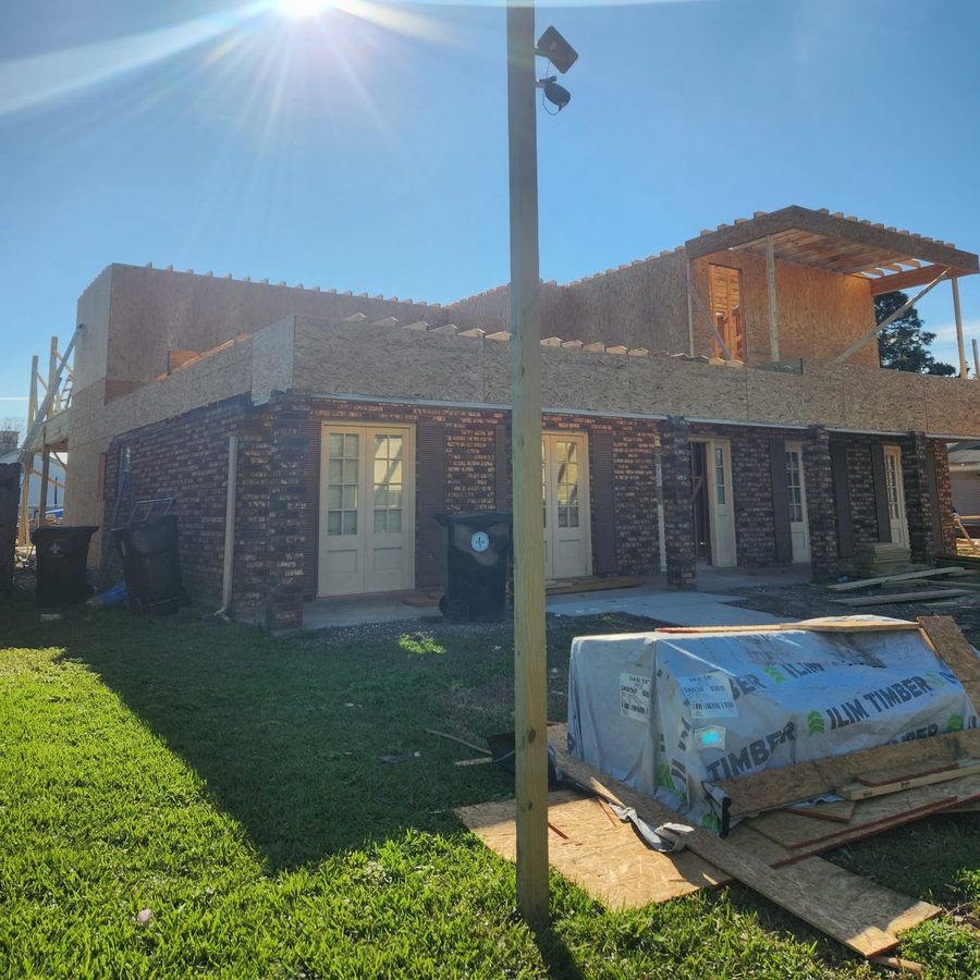 Brick home with a new upper story framed and sheathed, sun overhead